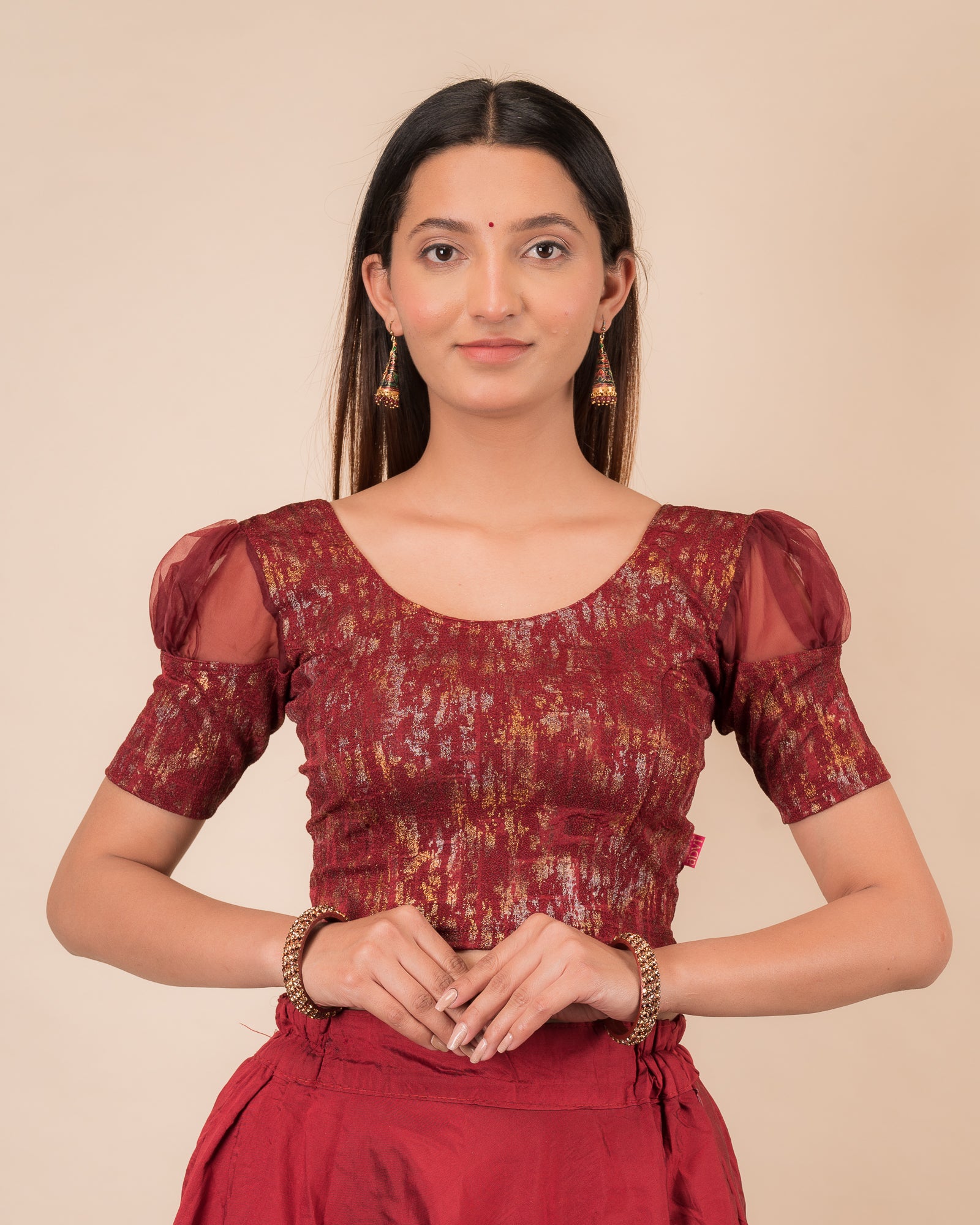Model wearing a stretchable foil-textured blouse with sheer puff sleeves and round neckline