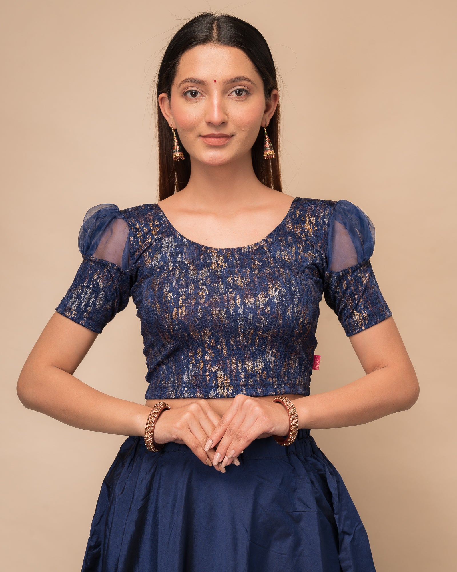 Model wearing a stretchable foil-textured blouse with sheer puff sleeves and round neckline