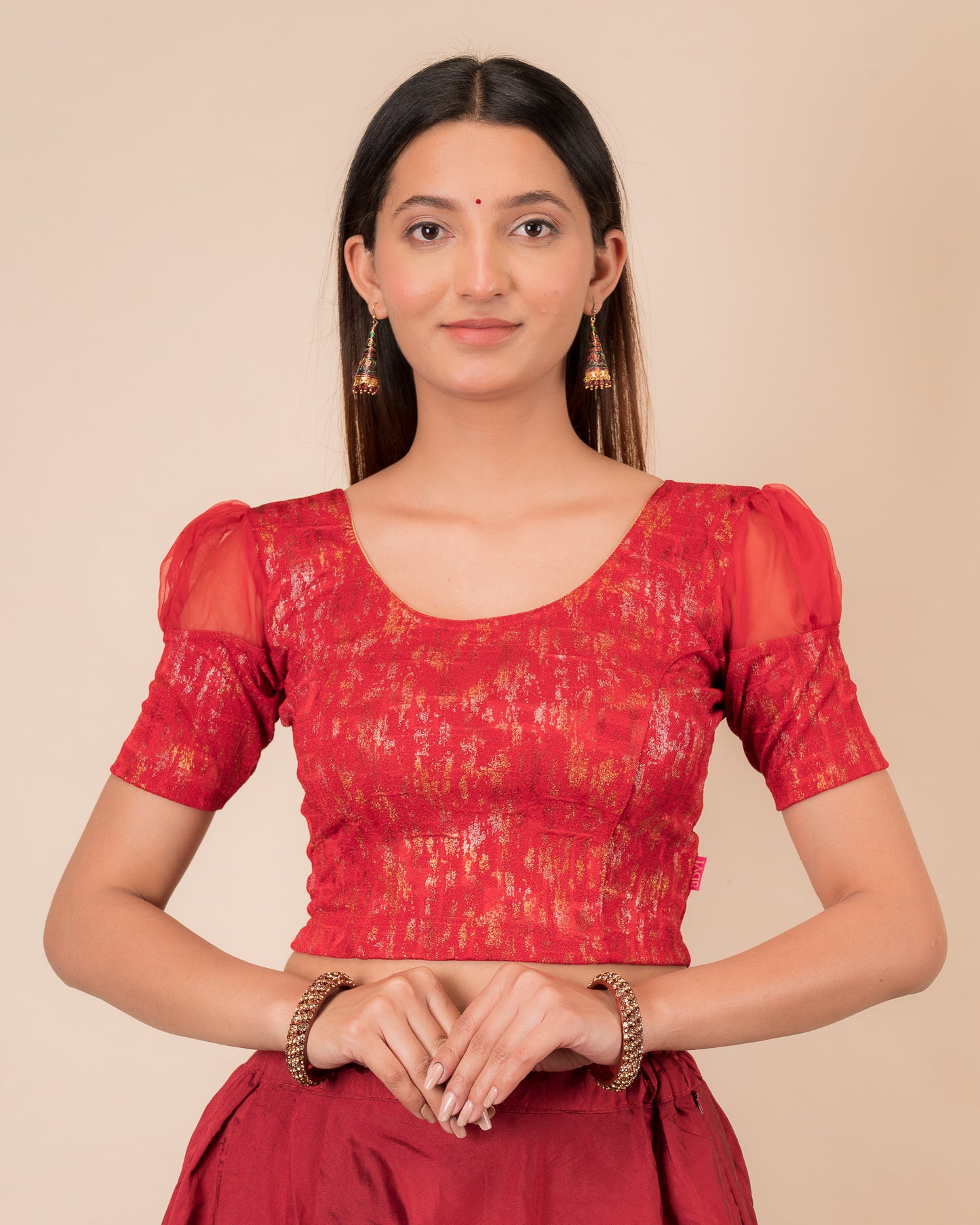 Model wearing a stretchable foil-textured blouse with sheer puff sleeves and round neckline