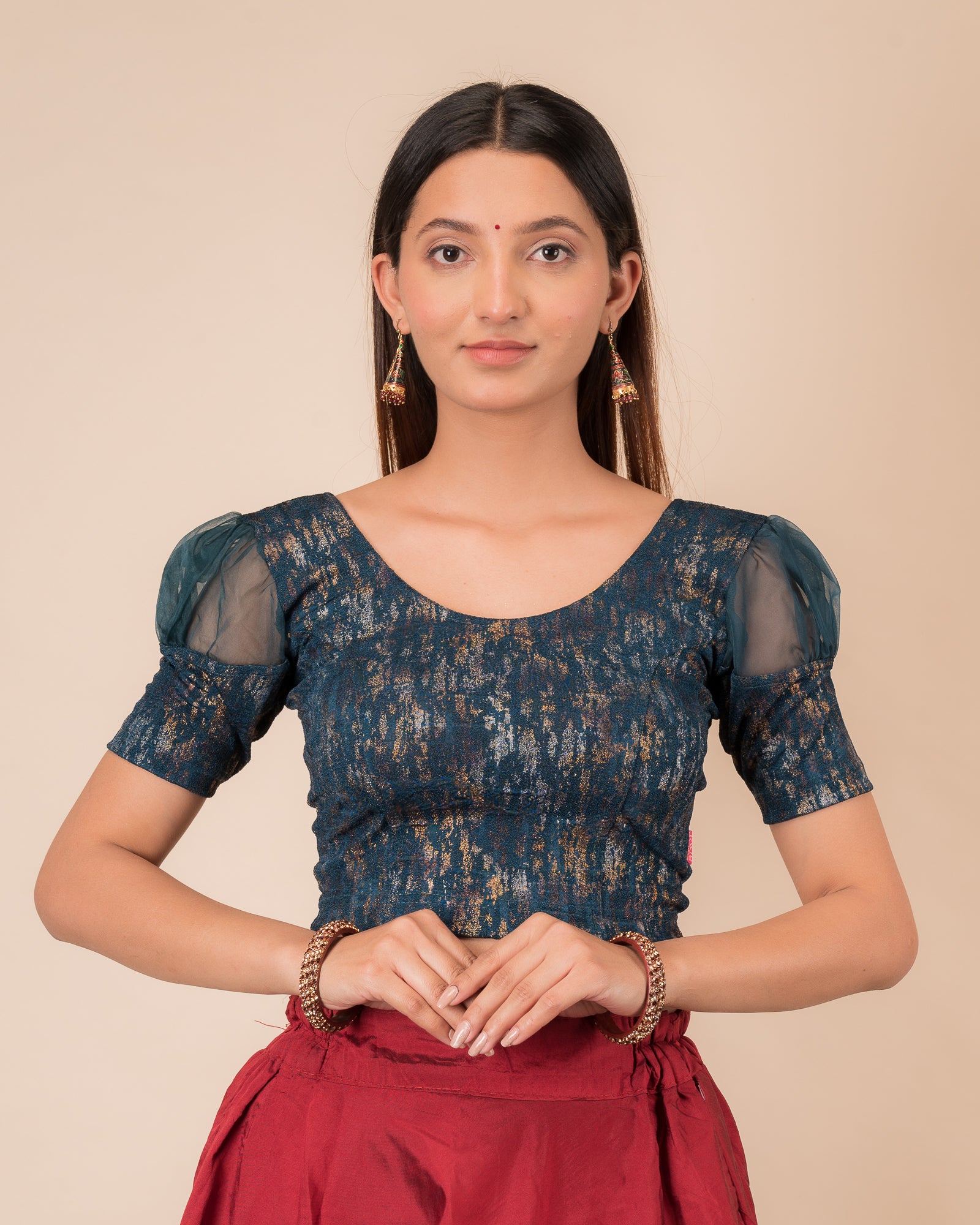 Model wearing a stretchable foil-textured blouse with sheer puff sleeves and round neckline
