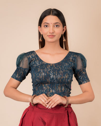Model wearing a stretchable foil-textured blouse with sheer puff sleeves and round neckline