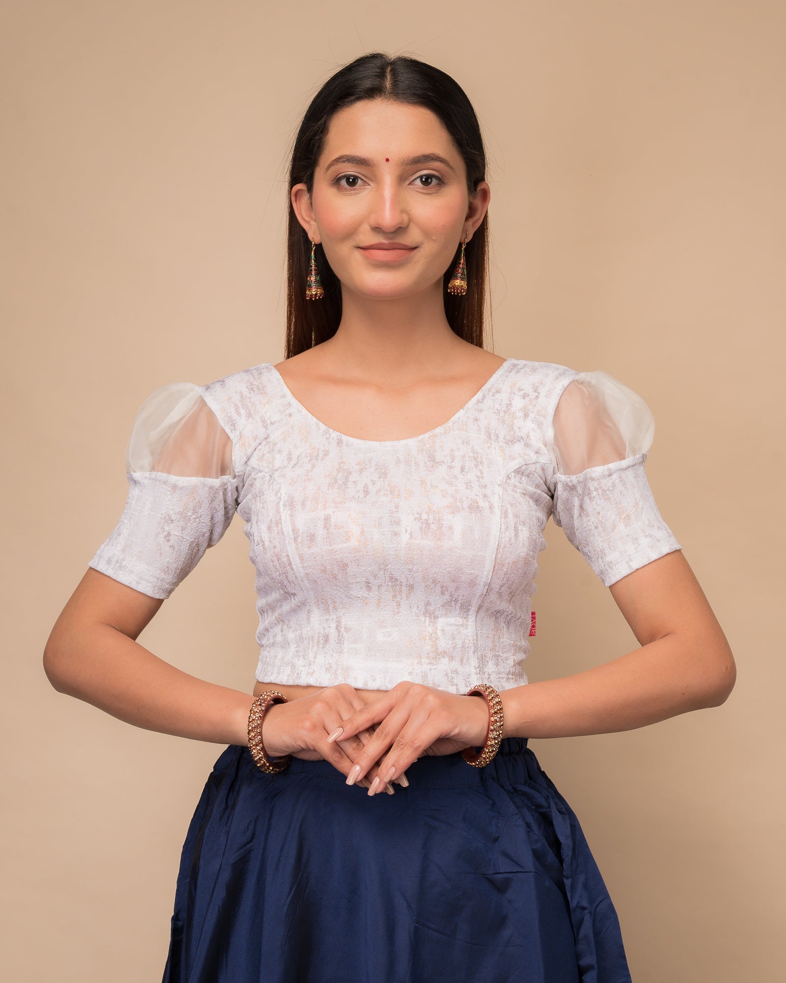 Model wearing a stretchable foil-textured blouse with sheer puff sleeves and round neckline