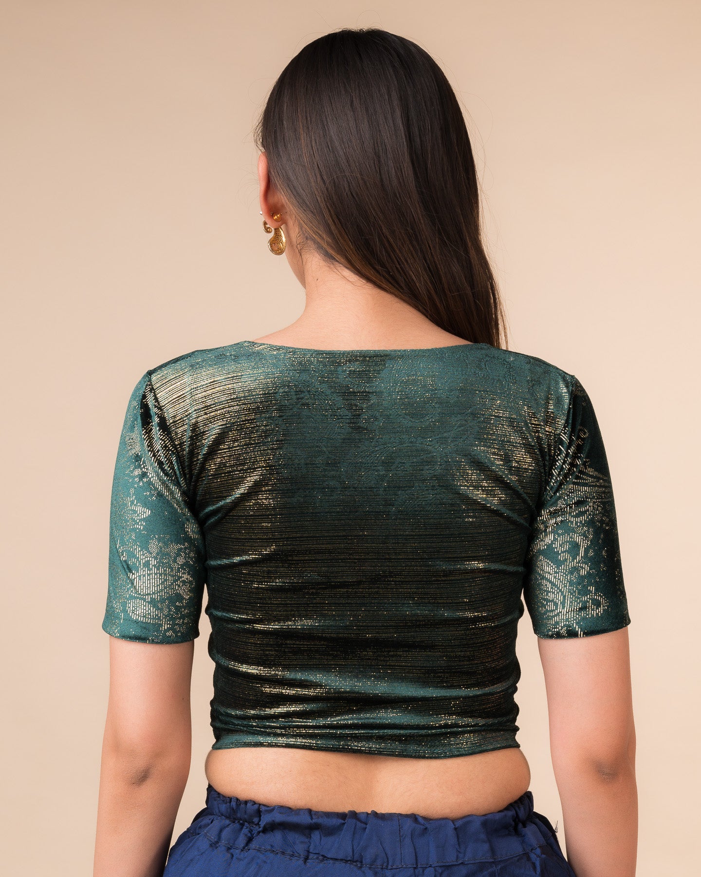 Rear view of the bottle green-colored velvet embellished stretchable choli-style blouse showcasing the deep round back design.