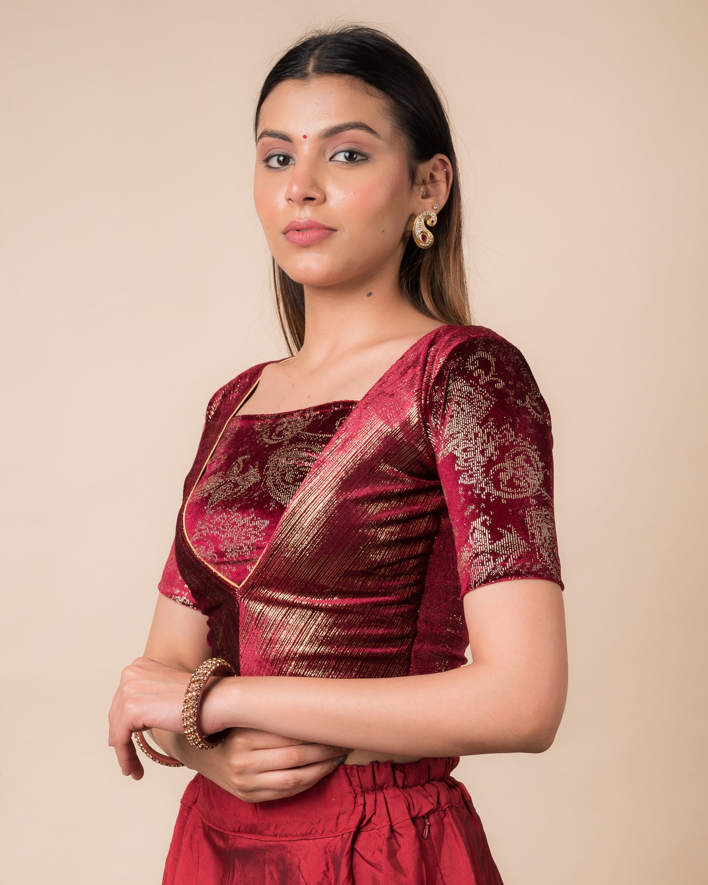 Side profile of the maroon-colored velvet embellished stretchable choli-style blouse highlighting the fit and sleeve length.
