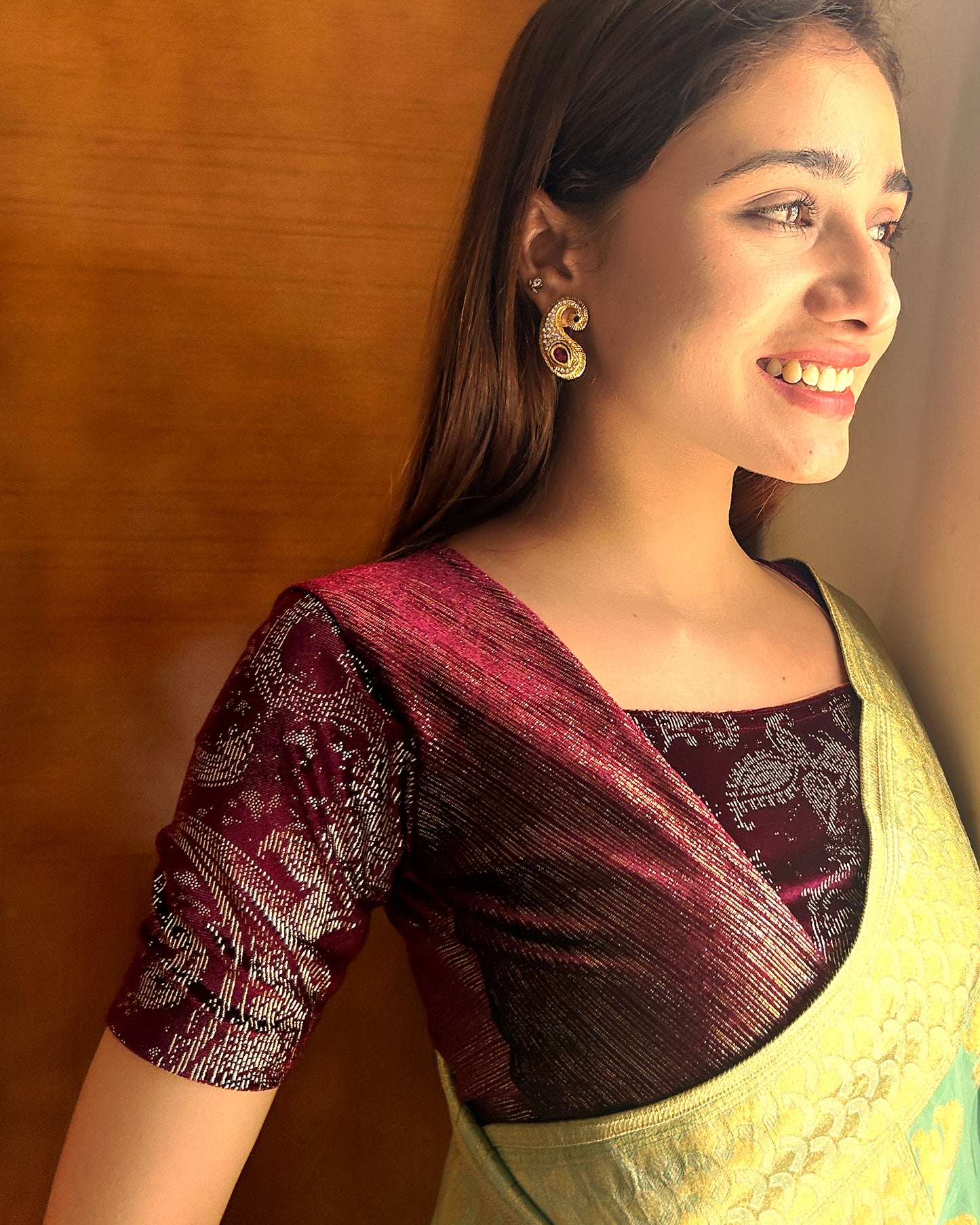 Model pairing the wine-colored velvet embellished stretchable choli-style blouse with a traditional saree, demonstrating a complete festive look.