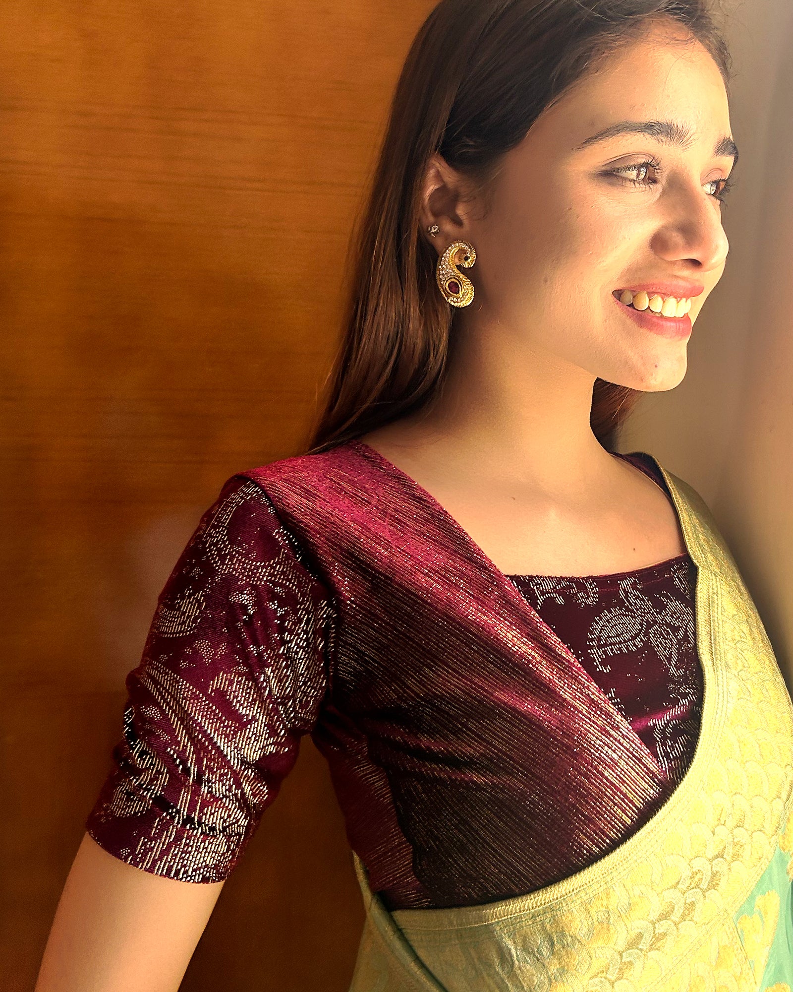 Model pairing the wine-colored velvet embellished stretchable choli-style blouse with a traditional saree, demonstrating a complete festive look.