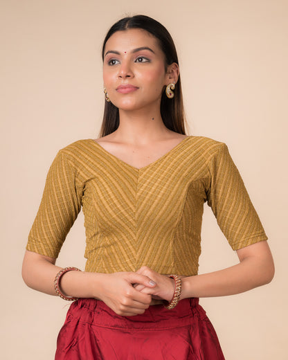Model wearing a dark gold zari stretchable readymade blouse with elbow sleeves and V-neckline.