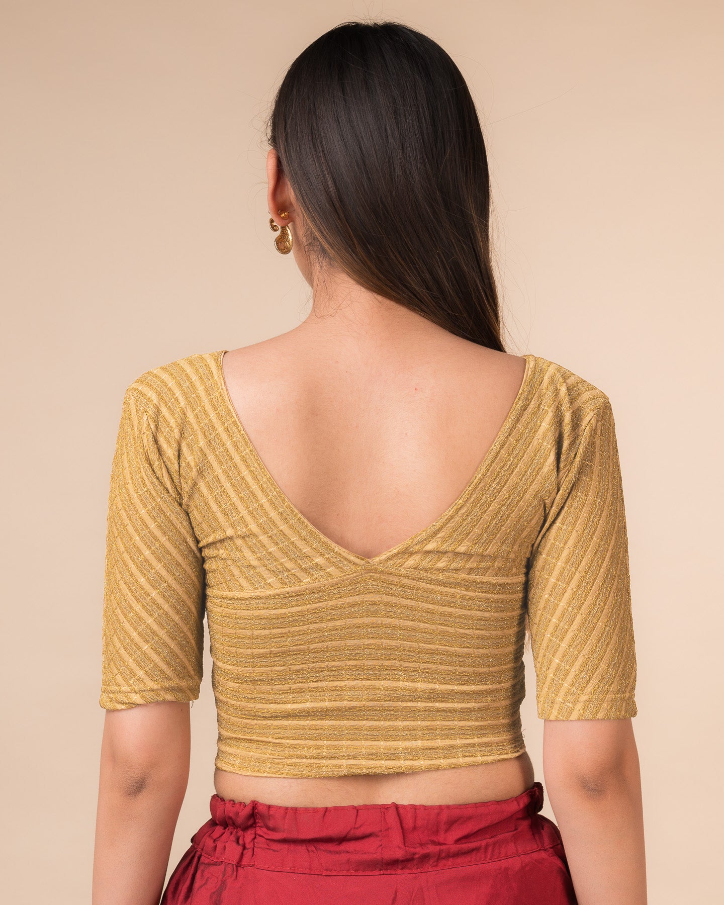 Rear view of the beige gold zari stretchable blouse showcasing the deep V-back design.