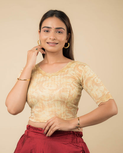 Model wearing a gold-colored stretchable readymade blouse with zari embroidery, elbow sleeves, and scalloped round neckline.