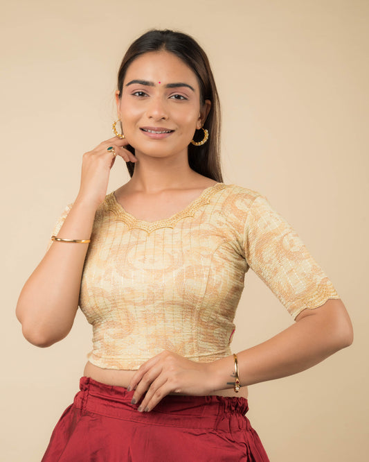 Model wearing a gold-colored stretchable readymade blouse with zari embroidery, elbow sleeves, and scalloped round neckline.