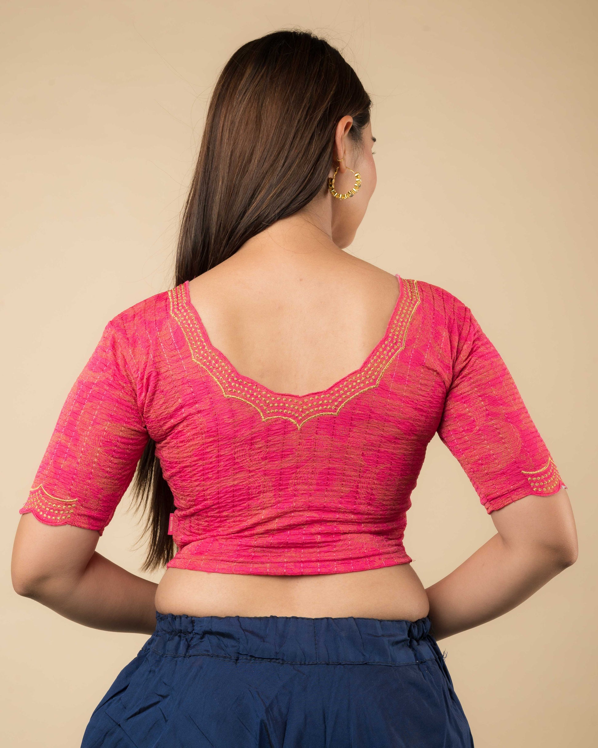 Rear view of the rani-colored stretchable blouse showcasing the back design and zari embroidery.