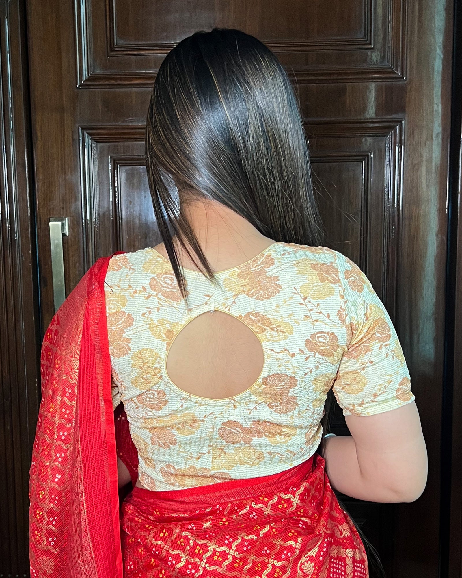 Model pairing the metallic floral stretchable blouse with a traditional saree,showcasing the peekaboo back design
