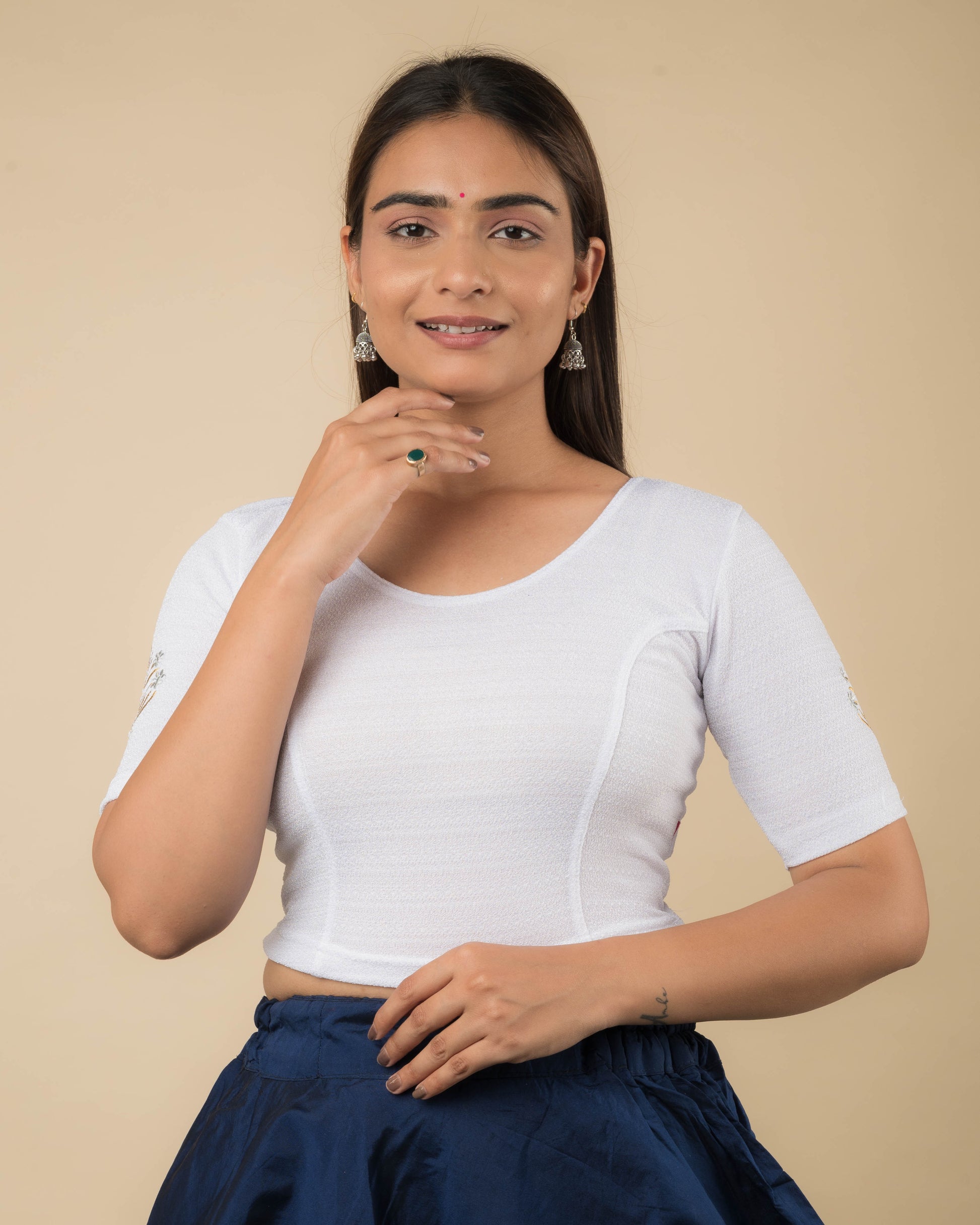 Model wearing a white buti embroidered stretchable readymade blouse with elbow sleeves and round neckline.
