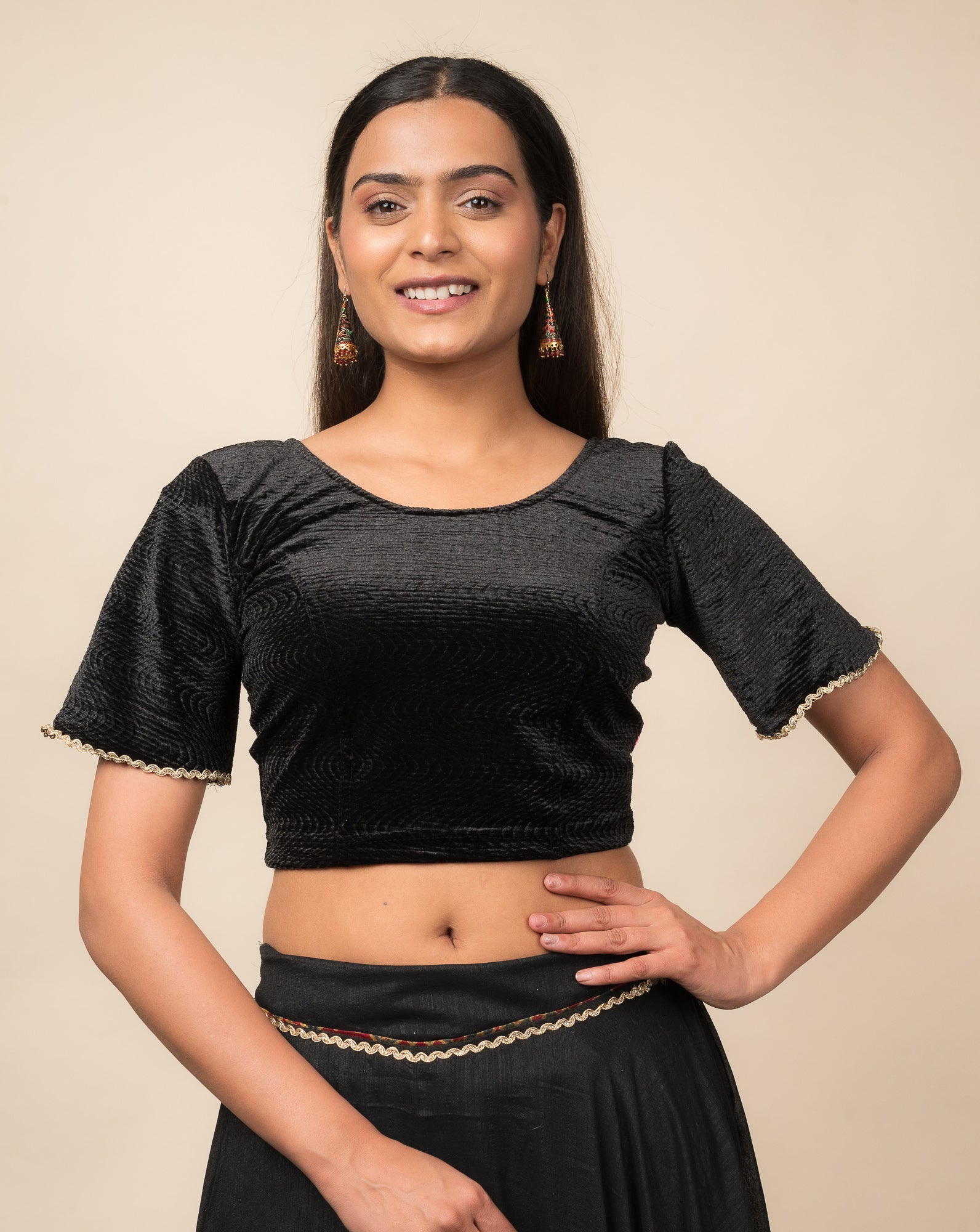 Model wearing a velvet stretchable readymade blouse with elbow-length bell sleeves and round neckline.