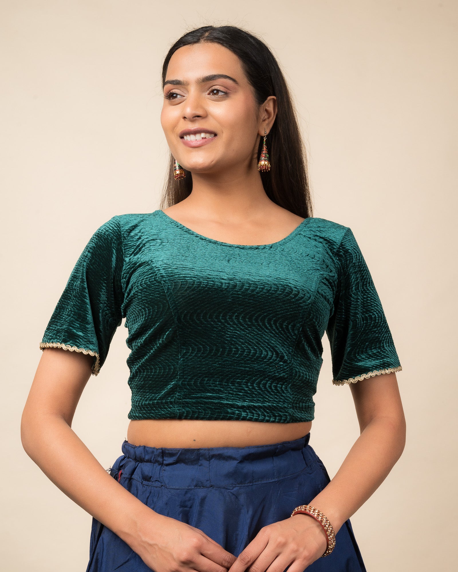 Model wearing a velvet stretchable readymade blouse with elbow-length bell sleeves and round neckline.
