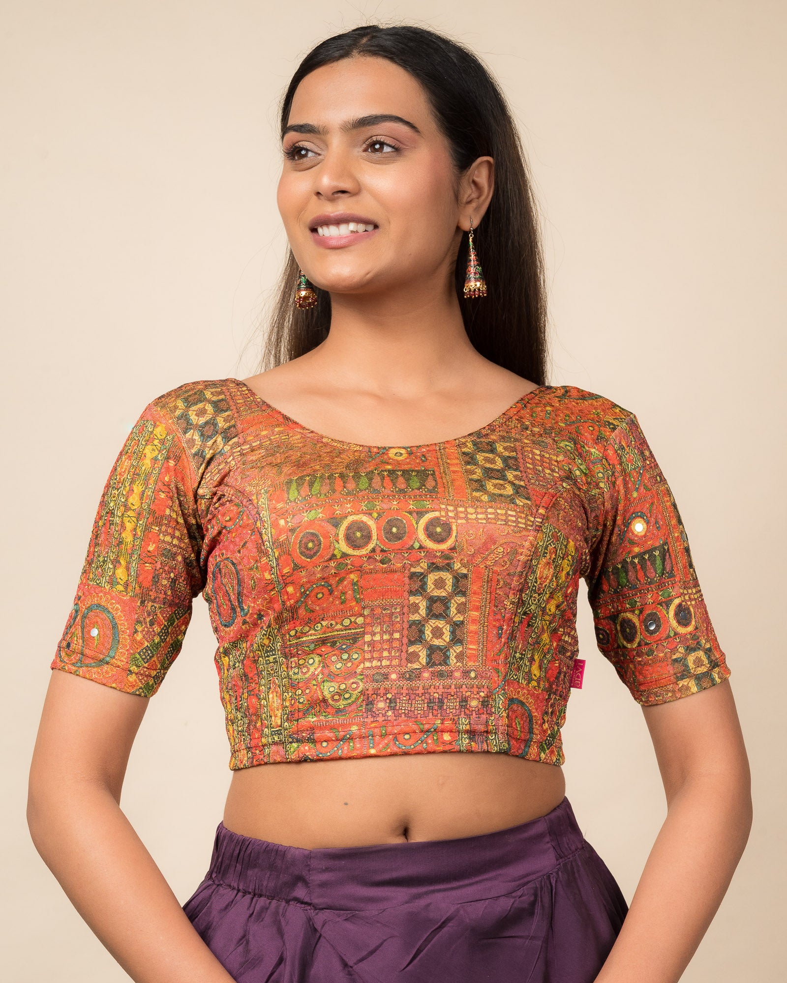 Model wearing a stretchable blouse with elbow sleeves and round neckline featuring ethnic mirror embellishments.