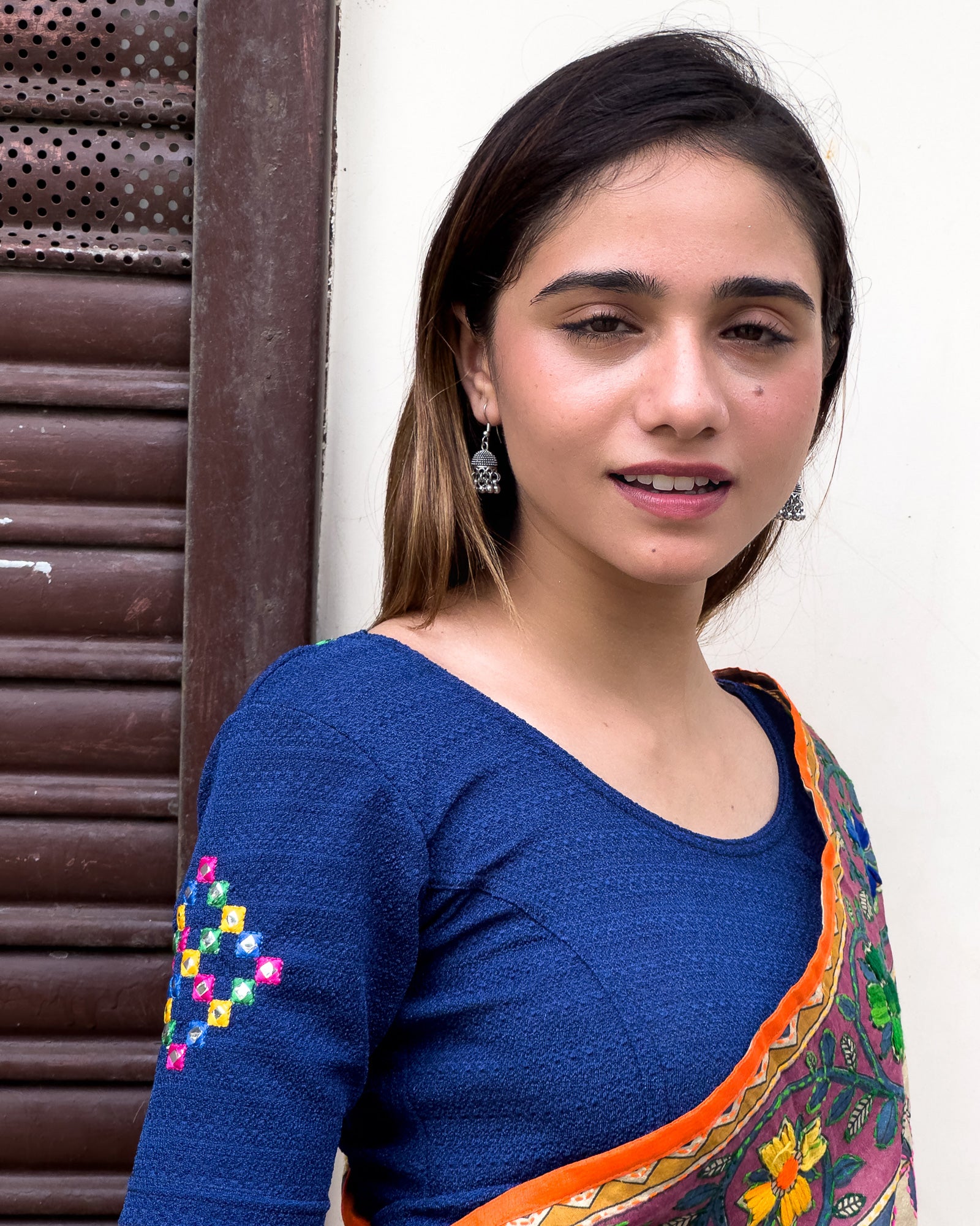 Model wearing a stretchable blouse with mirror embroidery on the neckline and sleeves.