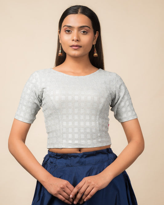 Model wearing a stretchable blouse with a boat neckline and elbow sleeves, featuring metallic embossed checks.