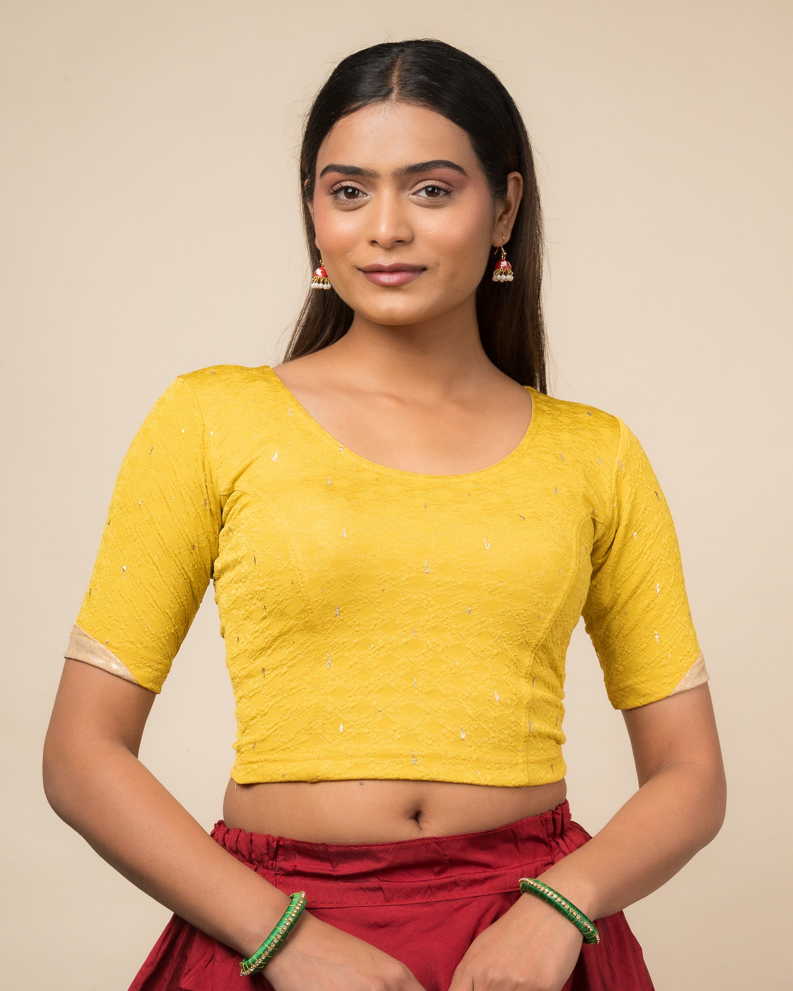 Model wearing a stretchable blouse with round neckline and elbow sleeves featuring metallic drop motifs.