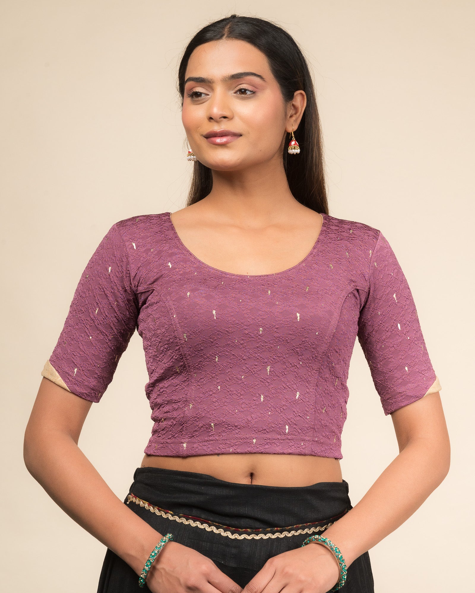 Model wearing a stretchable blouse with round neckline and elbow sleeves featuring metallic drop motifs.