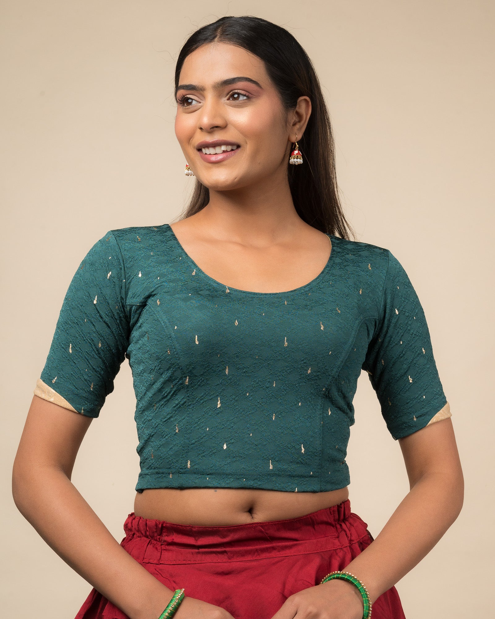 Model wearing a stretchable blouse with round neckline and elbow sleeves featuring metallic drop motifs.