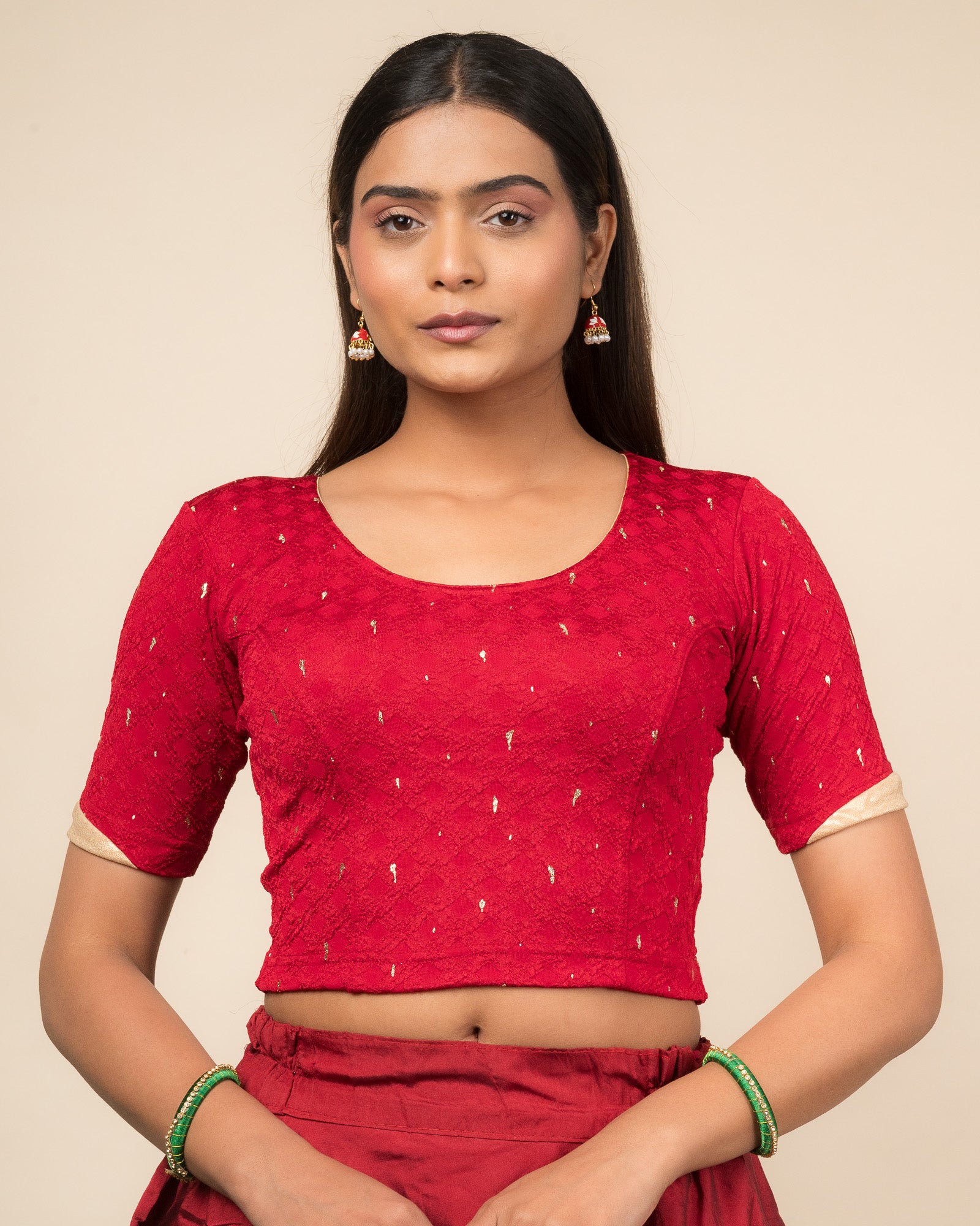 Model wearing a stretchable blouse with round neckline and elbow sleeves featuring metallic drop motifs.