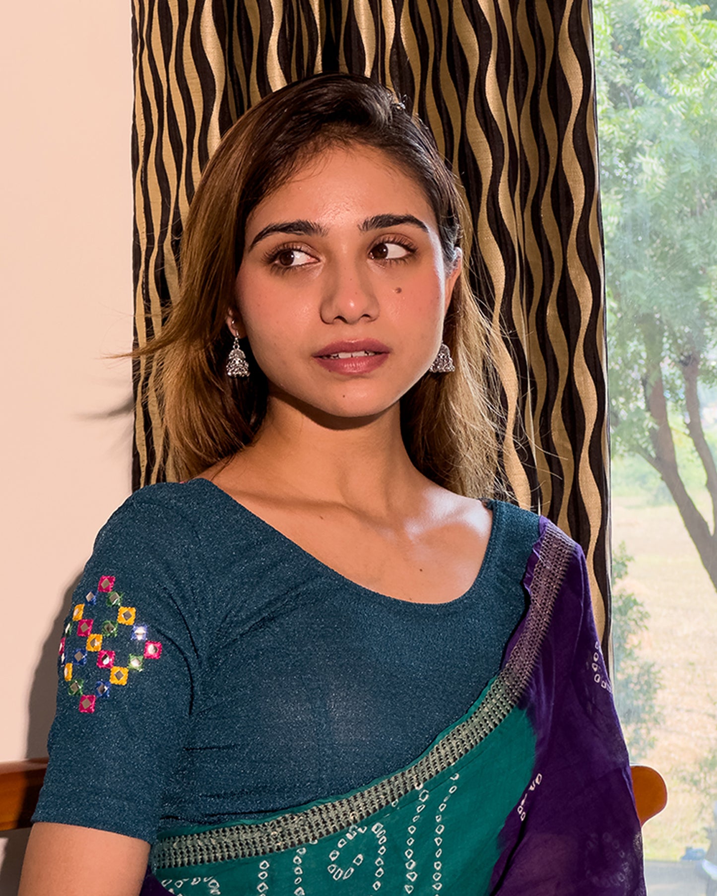Model wearing a stretchable blouse with mirror embroidery on the neckline and sleeves.